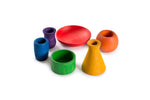 A collection of colorful wooden objects is displayed on a white background. The objects include a red bowl, an orange rounded vase, a yellow conical vase, a green cylindrical container, a blue ribbed vase, and a purple small vase. Each object is uniquely shaped and brightly colored, showcasing a variety of forms and hues.